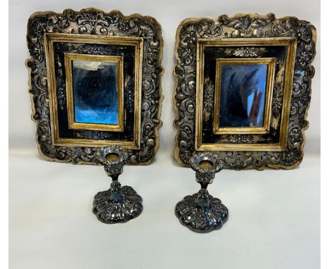 A pair of decorative framed mirrors together with a pair of plated candle stick holders.