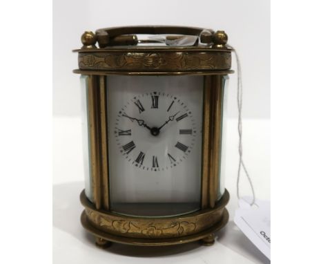 A small oval brass and glass carriage clock with roman numerals Condition Report: Available upon request