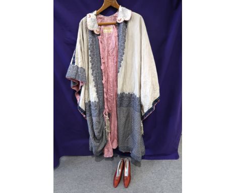 A cream ground embroidered Bedouin cloak with pink rope tassel fastenings and a pair of 1920s ruby silk shoes Condition Repor