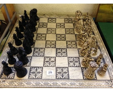 A late 20th century resin chess set and board, the pieces modelled as French Louis XV style figures with accompanying table s