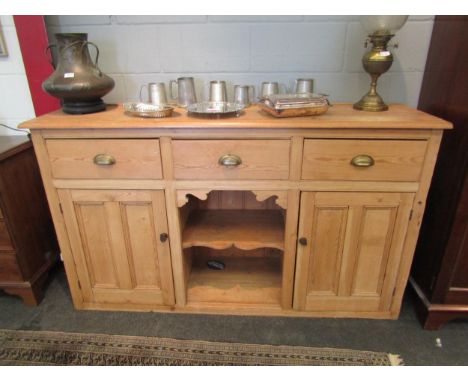 A 19th/20th Century pine dresser base. Three drawers over two cupboard doors flanking a shelved recess. 100cm x 173cm x 46cm 