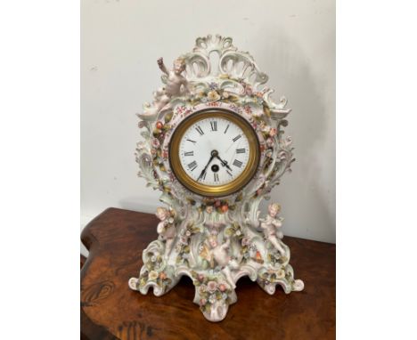 A late 19th Century highly ornate ceramic mantel clock decorated in the Rococo style with putti and flowers. Circular enamel 