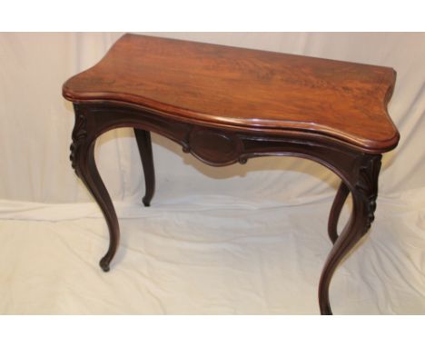 A 19th century rosewood serpentine-fronted turn-over-top card table with baize lined playing surface on carved scroll-shape l