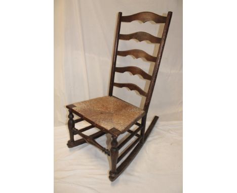 A 19th century ash and elm country-style ladder back rocking chair with rush-work seat on cabriole legs