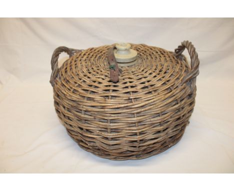 A wicker-bound glass carboy, adapted as a table lamp