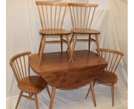 A 1960's Ercol pale elm circular drop-leaf dining table together with a set of four spindle-back dining chairs with polished 