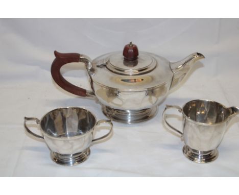 A good quality silver three-piece tea set comprising circular teapot with polished wood handle, matching two-handled sugar ba