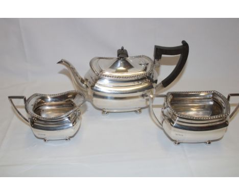 A George VI silver oval three-piece tea set comprising a rectangular tea pot with hinged lid and ebonised handle, matching tw