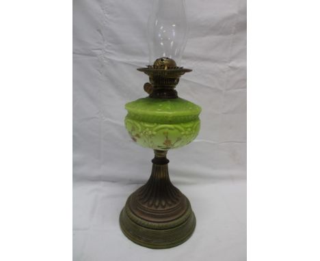 A Victorian brass oil lamp with green tinted glass reservoir and circular ceramic base