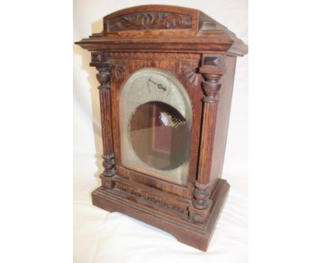 An Edwardian carved oak bracket clock case only with silvered part arched dial