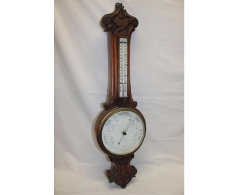 A good quality aneroid barometer with circular ceramic dial below thermometer in carved oak case