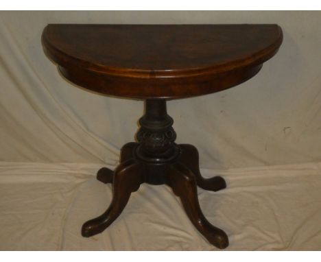 A Victorian inlaid walnut semi-circular turnover top card table with baize lined playing surface and central column on scroll