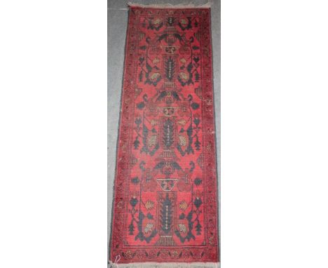 An Eastern-style wool rectangular runner with geometric decoration on red ground 60" x 21"