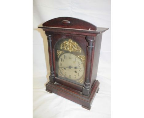 A German bracket-style mantel clock with silvered and gilt arched dial in stained wood rectangular case