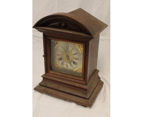 A German bracket clock with gilt and silvered square dial in stained oak arched case