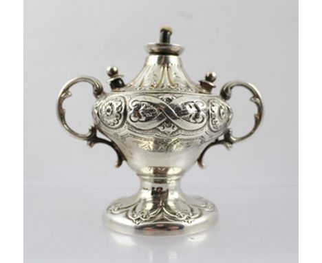 A LATE VICTORIAN WHITE METAL TABLE CIGAR LIGHTER of twin handled urn design with repousse decoration, 8.5cm high 