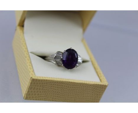 AN AMETHYST AND DIAMOND CLUSTER RING having central oval step cut amethyst, approx 3.95ct with nine baguette cut diamonds to 