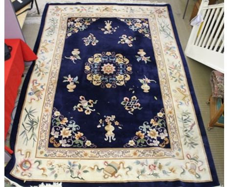 A CHINESE EUROPEAN QUALITY WOOL FLOOR CARPET, having floral central medallion with various "precious objects", on deep blue g