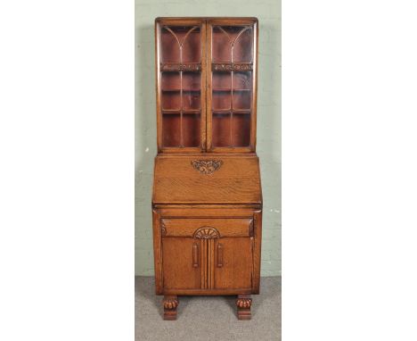 A carved oak bureau bookcase, with glazed top with adjustable shelving and fall down front revealing fitted interior above dr