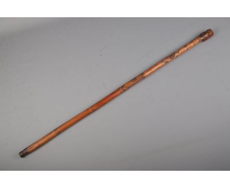 A Chinese cane walking stick with carved skeletons along the body and Buddha &amp; Devil carved on pommel.  