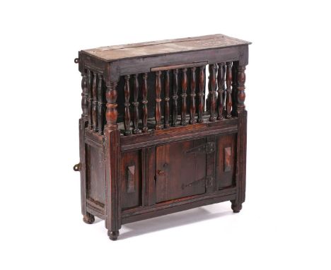A fruit wood dole cupboard, 17th century and later , the upper section enclosed by turned spindles and a hinged single door, 