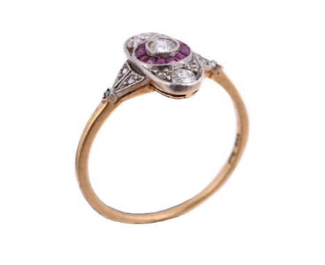 A diamond and ruby panel ring, the oval panel with a circlet of calibré cut rubies, centred with an old cut diamond, with ros