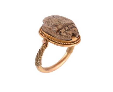 A scarab dress ring, the carved stone scarab within a ropetwist swivel setting, to ropetwist accented shoulders, finger size 