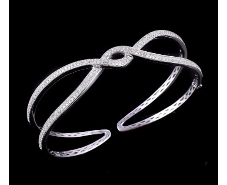 A diamond set hinged bangle, the crossover bangle set with eight cut diamonds, approximately 1 carat total, to a polished bac