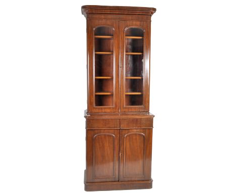 A tall 19th Century Victorian mahogany library bookcase cabinet. Flared pediment top with twin arched glazed doors revealing 