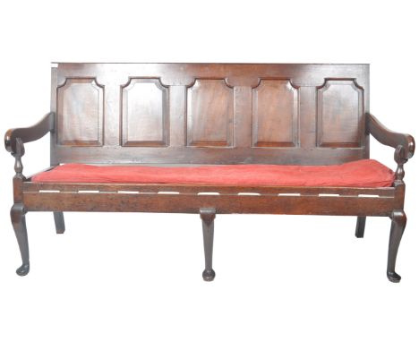 A 19th Century carved oak settle bench having a fielded panel back with large armrests and red velour cushioned seat. The set