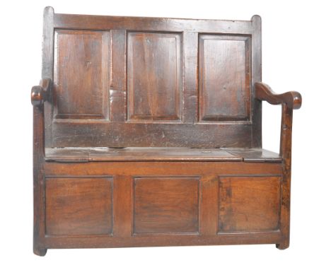 An 18th Century oak hall settle bench / monks bench having a triple fielded panel back with penny scroll end arm rests. The s