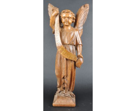 A 20th century oak carving of an angel. Carved from a single piece of wood, posed as a standing figure with feathered wings d