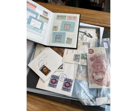 A collection of first day covers including silver jubilee together with a book of world stamps and a 10 shilling note 