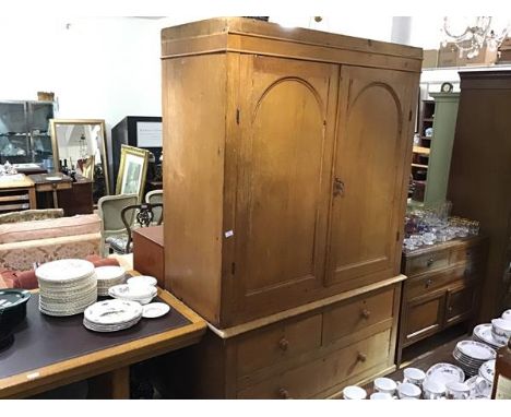 A 19th century pine press cupboard, the pair of arched panel doors enclosing two shelves, with three drawers below, lacking c