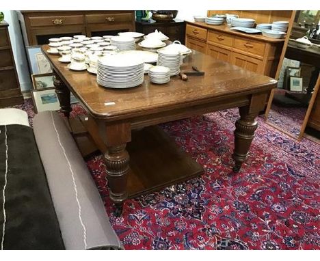 A late Victorian oak telescopic dining table, the rectangular top enclosing three additional leaves, raised on moulded balust
