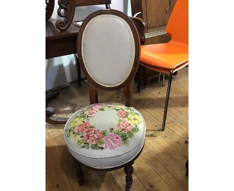 A late Victorian walnut nursing chair c.1890, the upholstered oval back above a tapestry seat on baluster shaped legs and cas