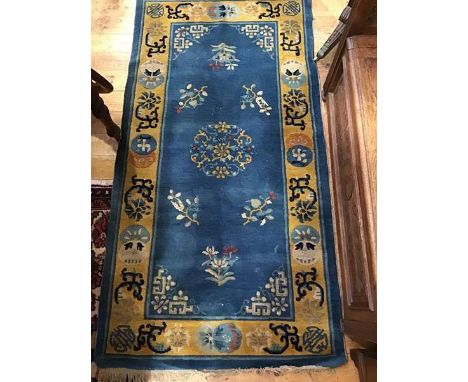 A Chinese wool rug, the centre panel with floral medallions, multiple flowerhead border (177cm x 93cm)