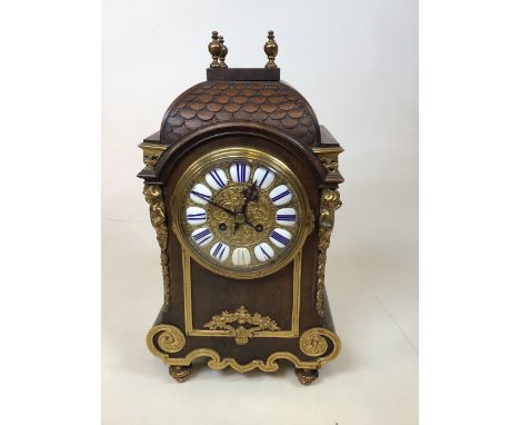 An oak cased early 20th century 8 day Clock with brass ormolu style decoration. With brass feet and finials. Fish scale decor