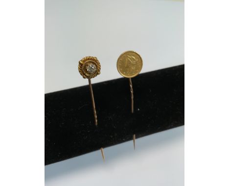 Two stick pins, one with an 1854 gold dollar and the other a yellow metal diamond studded pin. 