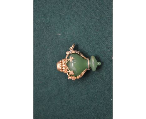 A yellow metal and jade pendant.