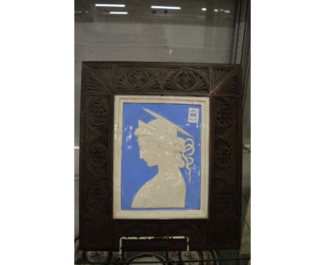 A Della Robia porcelain plaque depicting a profile portrait of a young lady mounted in a carved wood frame.