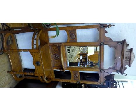 An early to mid 20th Century carved light oak hall stand, having an assortment of hooks, surrounding a bevelled edged mirror 