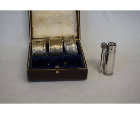 A sterling silver Dunhill service lighter, together with three various silver and silver-plated napkin rings.