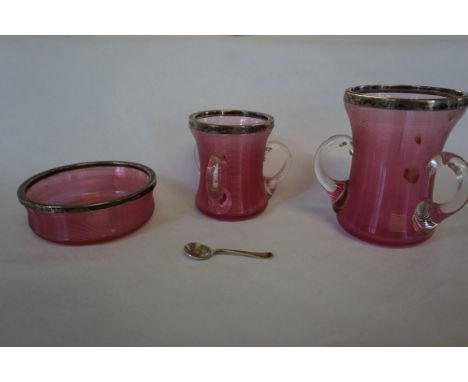 Two early 20th Century cranberry glass loving cups, each with hallmarked silver collars, together with a similar bowl.