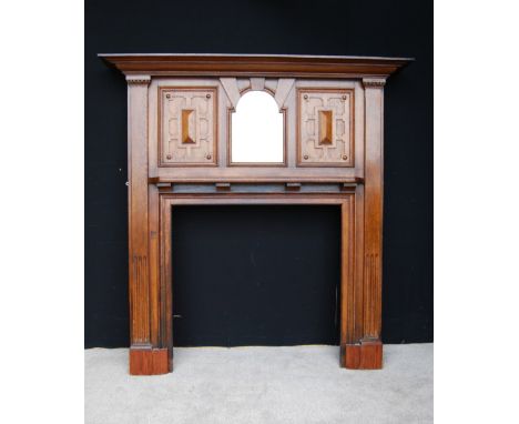 Oak fire surround, the projected moulded cornice over a central mirror, panels and shelves, raised on fluted jams, 184cm wide
