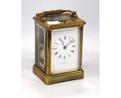 Brass repeating carriage clock mounted by a loop handle over white enamelled face, Roman numerals and plinth base, striking c