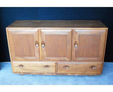 Ercol Golden Dawn sideboard fitted with three drawers flanked by cupboards, 130cm long and 87cm high.