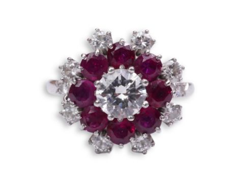 A ruby and diamond ring of cluster design, set with a brilliant-cut diamond weighing approximately 0.70 carats, within a bord