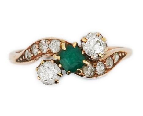 An emerald &amp; diamond ring, early 20th century, of crossover design, set with a step-cut emerald between circular-cut diam