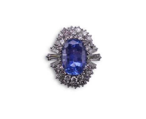 A sapphire and diamond ring, of cluster design, set with an oval sapphire weighing approximately 5.00 carats, within a border